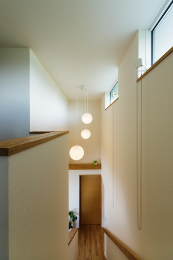 異なるサイズの丸いシャンデリア照明がやわらかく階段室を照らす