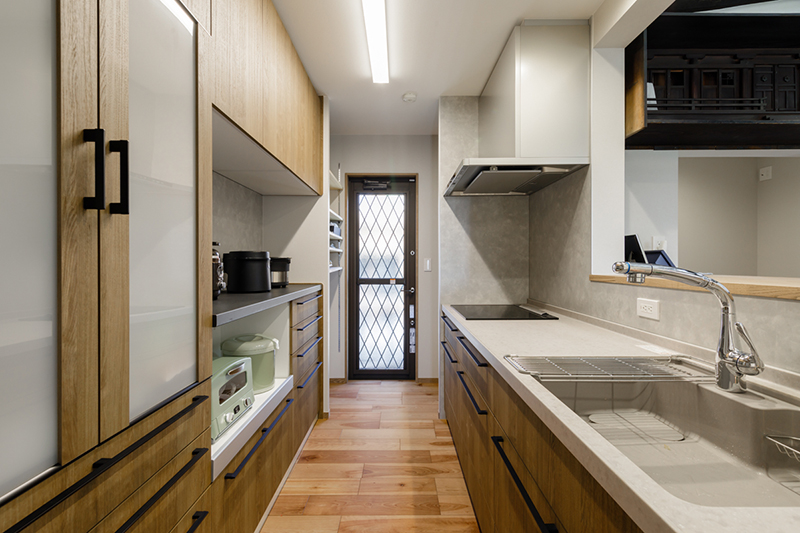 清潔感漂う最新のシステムキッチン。収納量たっぷりの家電収納と、キッチン奥にはパントリースペースも。
